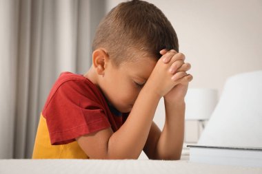 Elleri birbirine kenetlenmiş tatlı küçük bir çocuk evde yatmadan önce dua ediyor.