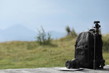 Dışarıdaki ahşap yüzeyde fotoğrafçının sırt çantası, kamera, tripod ve dizüstü bilgisayarı. Metin için boşluk