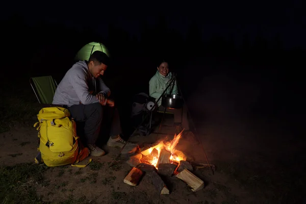 夜のキャンプでたき火の近くに座っているカップル — ストック写真