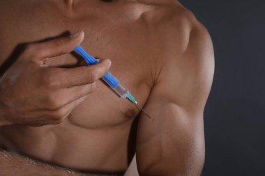 Atletik adam kendine gri arka planda iğne yapıyor, yakın plan. Doping kavramı