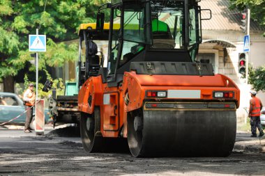 MYKOLAIV, UKRAINE - Ağustos 05, 2021: İşçiler şehir caddesinde paten ile yeni asfalt döşüyorlar. Yol onarım servisi