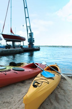 Nehir kenarındaki plajda kürek çeken modern kanolar. Yaz kampı aktivitesi