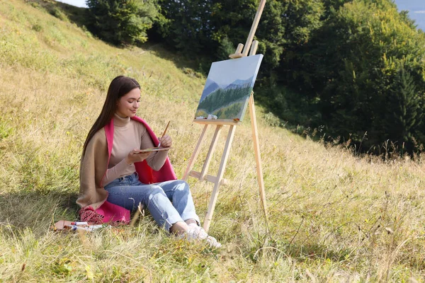 森の近くに筆でイーゼルを描く若い女性 — ストック写真