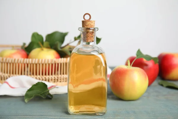 天然苹果醋和新鲜水果放在蓝色木制桌子上 — 图库照片