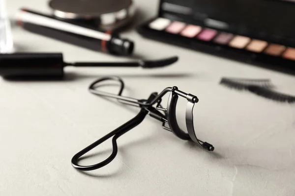 Eyelash curler on grey table, closeup. Makeup tool