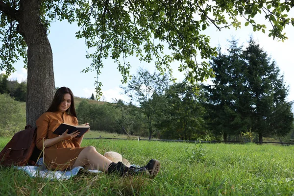Młoda Kobieta Czyta Książkę Pod Drzewem Łące — Zdjęcie stockowe