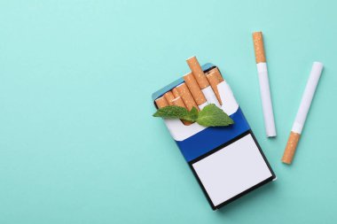Bir paket mentollü sigara ve turkuaz arka planda nane şekeri. Metin için boşluk