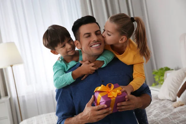 Man receiving gift for Father\'s Day from his children at home