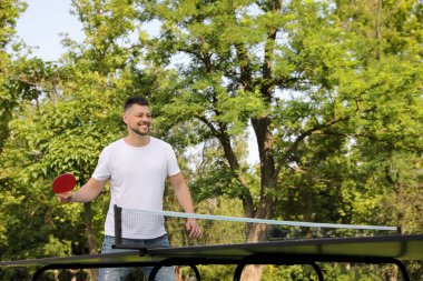 Mutlu adam yaz günü dışarıda masa tenisi oynuyor.