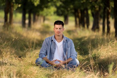 İnsan güneşli bir günde ormanda meditasyon yapıyor.