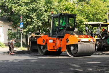 MYKOLAIV, UKRAINE - Ağustos 05, 2021: İşçiler şehir caddesinde ağır makinelerle yeni asfalt döşüyorlar. Yol onarım servisi