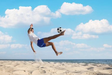 Sahilde futbol oynayan bir adam.
