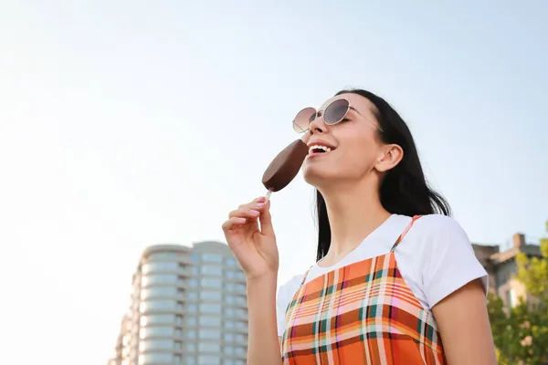 美しい若い女性が街の通り 低角度のビューでチョコレートで釉アイスクリームを食べている テキストのスペース — ストック写真