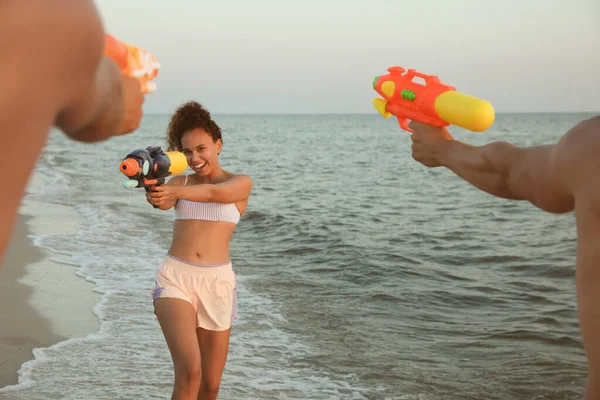 Friends with water guns having fun on beach