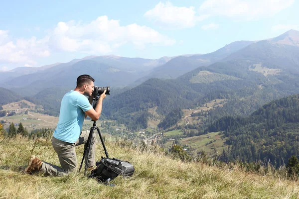 三脚の上で現代的なカメラで山の風景の写真を撮る男屋外 — ストック写真