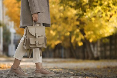 Şehir caddesinde şık bej sırt çantalı genç bir kadın, yakın plan. Metin için boşluk