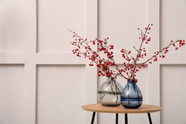 Kırmızı böğürtlenli Hawthorn dalları, ahşap masa üzerinde, kapalı alanda ışık duvarı yakınında, metin için boşluk