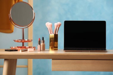 Odasında modern laptop ve makyaj ürünleri olan ahşap masa.