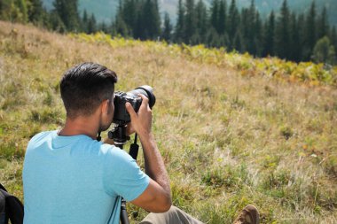 Profesyonel fotoğrafçı dağlarda modern kamerayla fotoğraf çekiyor. Metin için boşluk