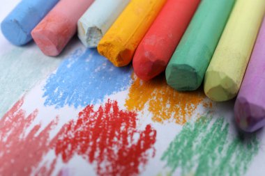 Renkli tebeşirler ve beyaz arka planda karalamalar, yakın plan. Çizim malzemeleri