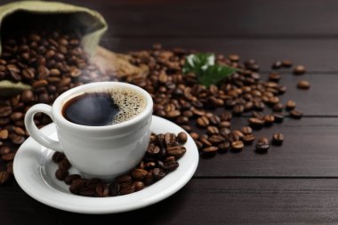 Ahşap masada bir fincan aromatik kahve ve fasulye. Metin için boşluk