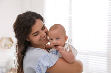 Evinin penceresinin yanında sevimli bebeğiyle mutlu genç bir anne.