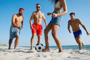 Sahilde futbol oynayan bir grup arkadaş.