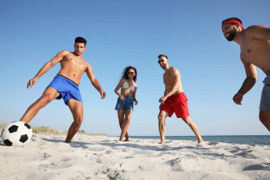 Sahilde futbol oynayan bir grup arkadaş.