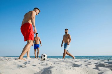 Sahilde futbol oynayan bir grup arkadaş.