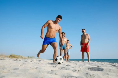 Sahilde futbol oynayan bir grup arkadaş.