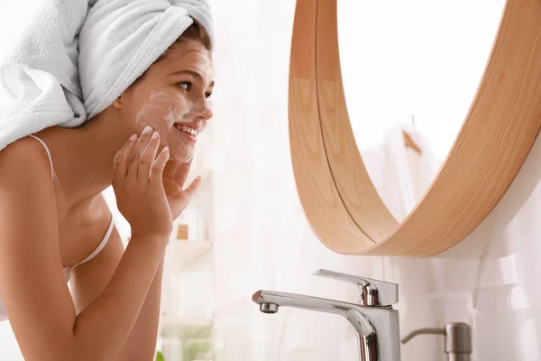 在浴室里 漂亮的少女在脸上涂上清洁剂泡沫 护肤化妆品 — 图库照片