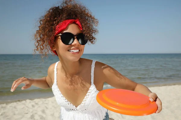 幸せなアフリカ系アメリカ人女性が晴れた日にビーチでディスクを投げる — ストック写真