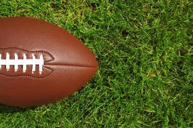 Yeşil çimlerin üzerinde Amerikan futbol topu, üst manzara. Metin için boşluk