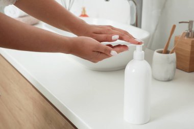 Güzel genç bir kadın banyoda çamaşır jeli kullanıyor, yakın plan. Cilt bakımı kozmetik