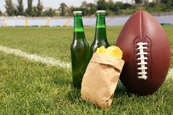 スタジアムの緑の芝生の上にビールやチップを持つアメリカのサッカーボール テキストのスペース — ストック写真