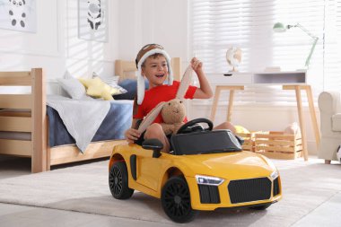 Küçük şirin çocuk evde oyuncak tavşan ve büyük oyuncak arabayla oynuyor.