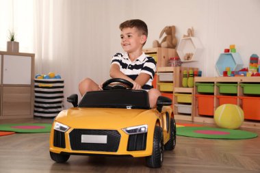 Evde büyük oyuncak araba kullanan sevimli küçük çocuk.