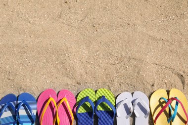 Kum üzerinde birçok farklı parmak arası terlik, düz yatış. Metin için boşluk