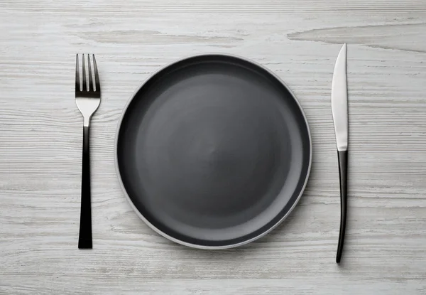 浅色木制桌子上新的深色盘子和餐具 — 图库照片