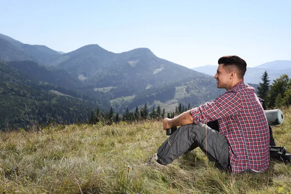 背着背包坐在地上欣赏高山美景的游客 — 图库照片