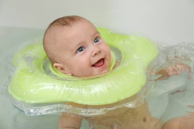 Banyoda şişme yüzükle yüzen şirin küçük bebek.