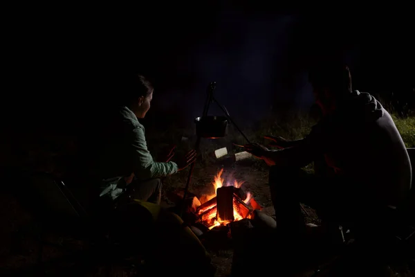 夜のキャンプでたき火の近くに座っているカップル — ストック写真