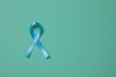 Turkuaz arka planda açık mavi farkındalık kurdelesi, üst manzara. Metin için boşluk