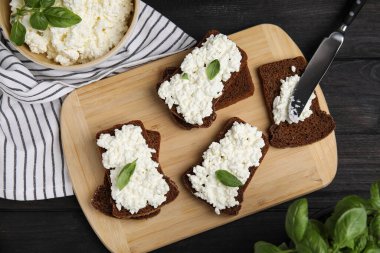 Süzme peynirli ekmek ve fesleğen siyah ahşap masa, düz yatıyordu.