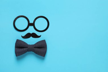 Kağıt gözlük, bıyık ve açık mavi arka planda papyon, düz yerde yazı için yer var. Babalar günü kutlaması.