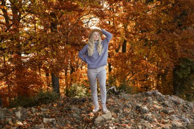 Sonbahar ormanında şapkalı güzel bir genç kadının tam boy portresi.