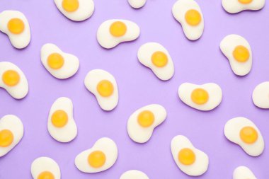 Leylak arka planında yumurta şeklinde lezzetli jöle şekerler, düz uzanmış.