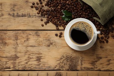 Bir fincan aromatik sıcak kahve ve fasulye ahşap masada, düz yerde. Metin için boşluk