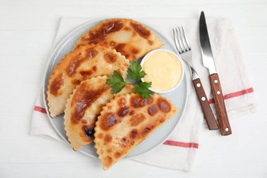 Beyaz masada servis edilen soslu leziz kızarmış chebureki.