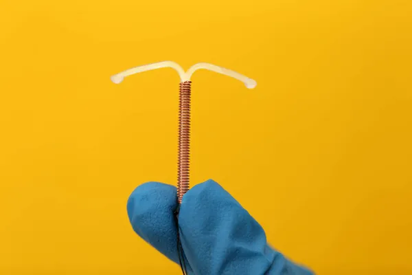 Médico Sosteniendo Dispositivo Anticonceptivo Intrauterino Forma Sobre Fondo Amarillo Primer — Foto de Stock